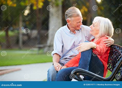 Mature Romantic Couple Sitting On Park Bench Together Stock Image