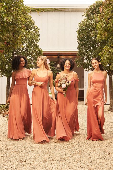 Four Bridesmaids In Orange Dresses Walking Through The Dirt Together