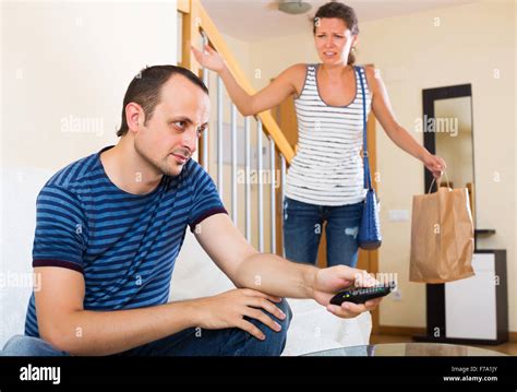 Sad Partner Asking Another For Forgiveness In Living Room Stock Photo