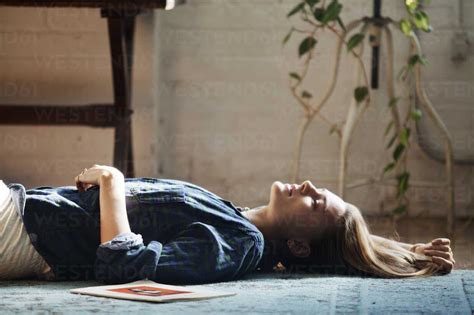 Side View Of Woman Lying On Floor At Home Lizenzfreies Stockfoto