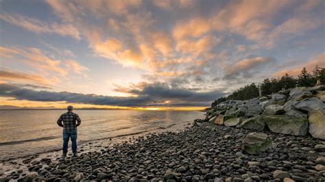 Man Standing On Rocky Shore During Sunset · Free Stock Photo