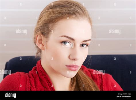 Beautiful Caucasian Woman Sitting Ona Couch And Wearing Red Pullover Indoor Background Stock