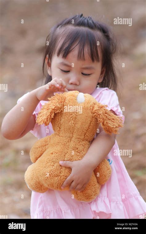Portrait Of Cute Girl Holding Teddy Bear While Standing Outdoors Stock