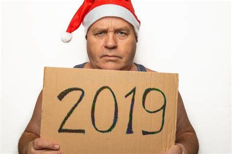 Portrait Of Funny Senior Man In Red Santa Claus Christmas Hat Holds Cardboard With Inscription