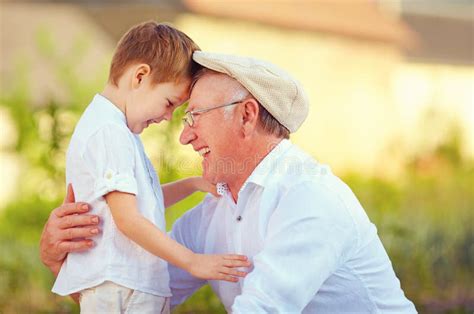 Happy Grandfather With His Grandson Reading Book Together At Home Stock