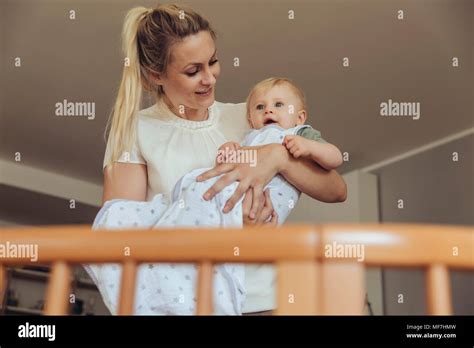 Mother Putting Baby In Its Crib To Sleep Stock Photo Alamy