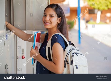 cute hispanic girl carrying some books and a backpack in high school