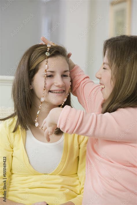 Teenage Girl Putting On A Necklace On Her Sister One With Birth Defect