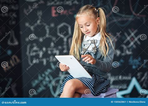 słodka blondynka w szkolnym mundurze trzymająca białe cyfrowe tablety tablica z formułami
