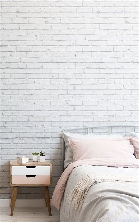 A White Brick Wall In A Bedroom Next To A Bed With Pink Sheets And Pillows
