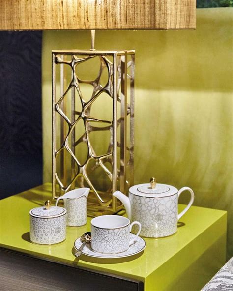 A Table With Two Cups And A Teapot On It Next To A Lamp That Is Turned On