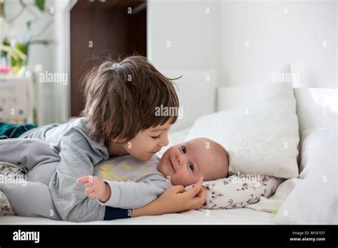 Two Children Baby And His Older Brother In Bed In The Morning Playing