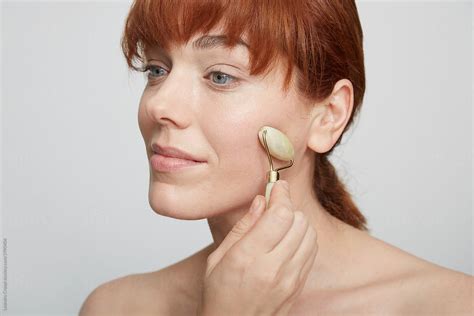 Beautiful Red Hair Woman Using Jade Roller By Stocksy Contributor