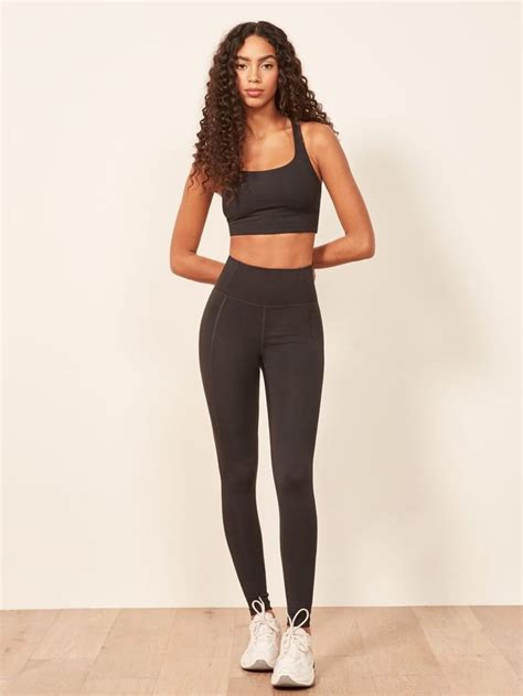 A Woman In Black Sports Bra Top And Leggings Standing On A Wooden Floor