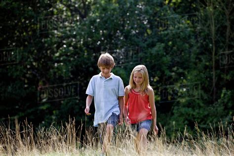 A Young Boy And Girl Walking Through A Field Stock Photo Dissolve