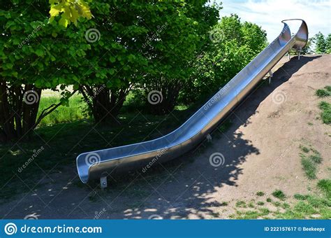 Stainless Steel Slide On A Playground With Grassy Hills Playground