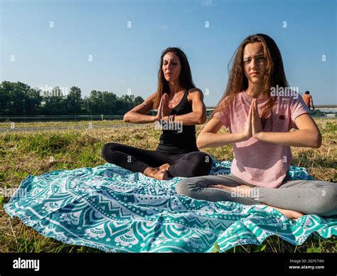 Madre e hija practicando yoga junto al río estilo de vida saludable