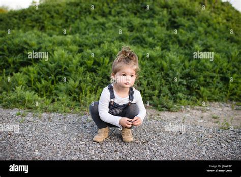 Cute Girl Crouching On Dirt Track Looking Away Stock Photo Alamy