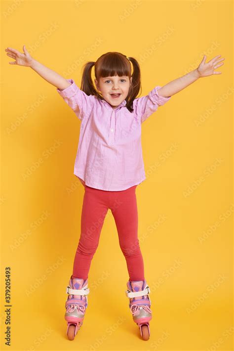 Happy Little Girl In Shirt And Leggins With Roller Skates Posing