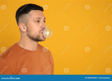 Handsome Man Blowing Bubble Gum On Orange Background Space For Text