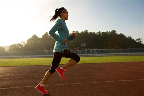 Runner Running During Sunny Morning On Stadium Track Stock Photo