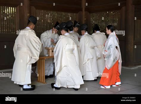 Shinto Priests And A Miko Maiden In Red Robe Take Part In Sake Drinking