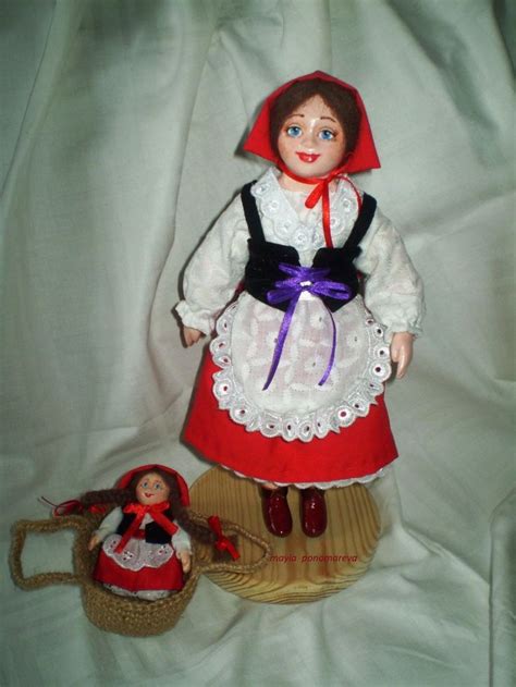 A Doll Is Standing Next To A Basket With A Doll In It On A White Sheet