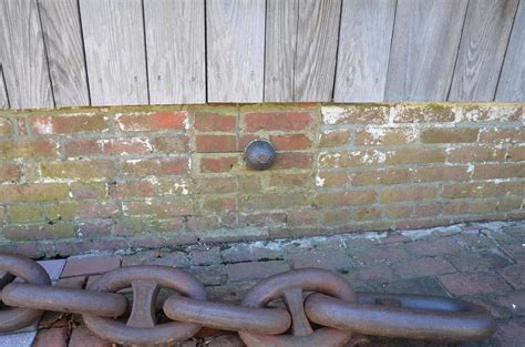 Small Iron Cannonball Stuck In Side Of Brick Building With Metal Chain