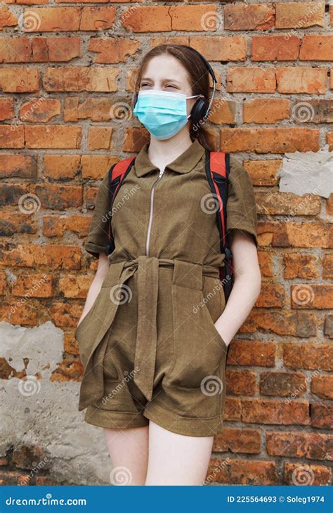 Schoolgirl Poses Against A Brick Wall In The Backyard Of The School