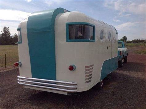 An Old Camper Trailer Is Parked On The Side Of The Road In Front Of A Field