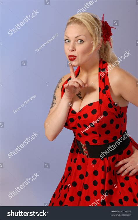 Fifties Style Attractive Blond Pinup Girl In Red Polka Dot Dress Gestures With Finger Humorous