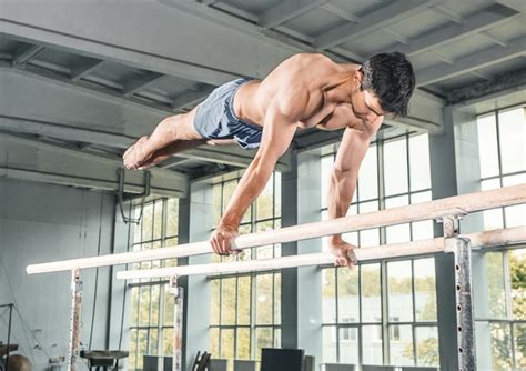 free photo male gymnast performing handstand on parallel bars