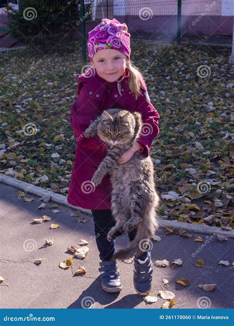 In Autumn A Girl Is Holding A Beautiful Stray Cat In Her Arms On The