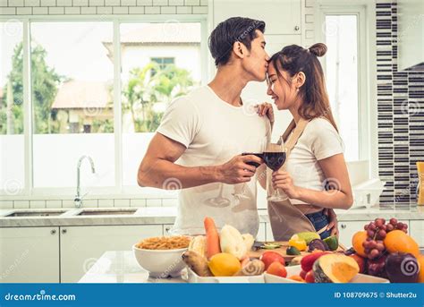 Asian Lovers Or Couples Kissing Forehead And Drinking Wine In Kitchen