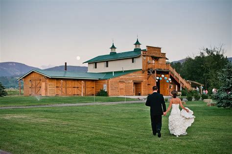 A Bride And Groom Walking In Front Of A Large Wooden Building With