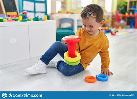 Adorable Caucasian Boy Playing With Hoops Toy Sitting On Floor At