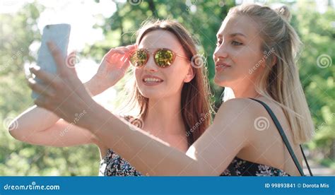 Close Up Portrait Of Two Young Cheerful Girls Having Fun And Making Selfie Outdoors Stock