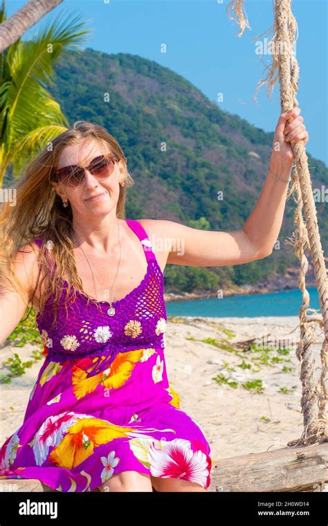 a mature woman with blonde hair swings on a swing on the seaside on the tropical island of koh