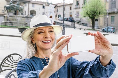 Mature woman taking smartphone selfie at sidewalk cafe, Fiesole ...