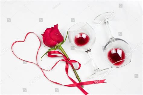 red heart of ribbon with red rose wine glasses with red wine and box on white bed honeymoon