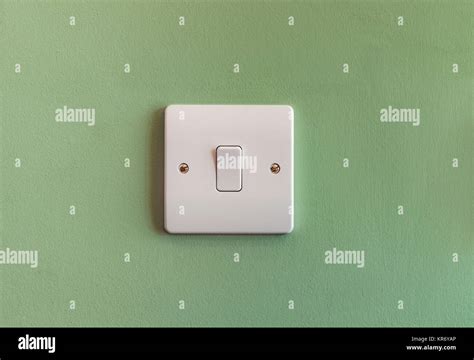 Uk Domestic Single Light Switch In White Plastic On A Green Coloured