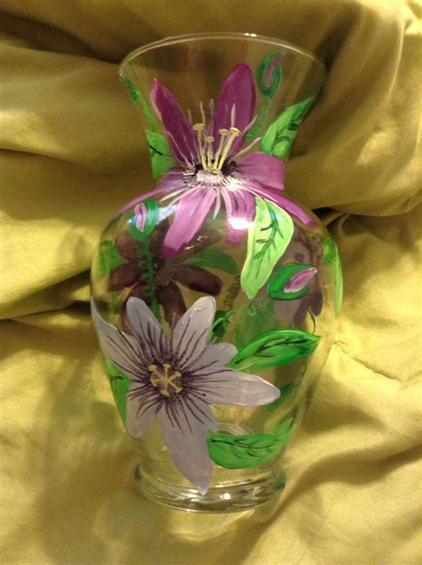 A Glass Vase With Purple Flowers Painted On The Outside And Green Leaves In The Inside