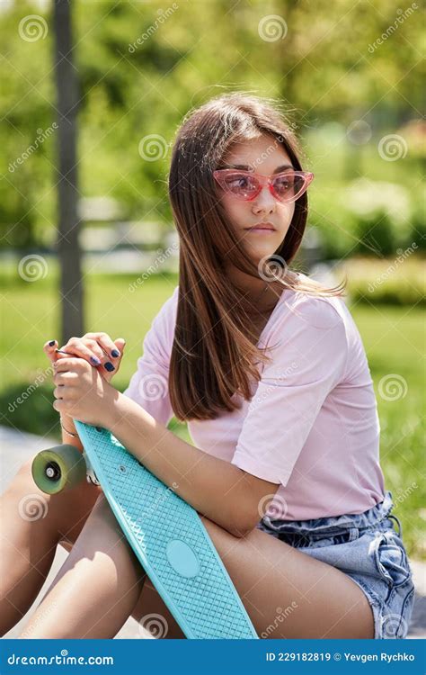 Beautiful Skateboarder Girl With Skateboard Sitting Outdoors Stock