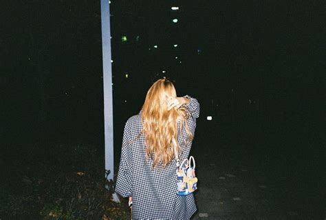 A Woman Walking Down The Street At Night With Her Hair Blowing In The Wind