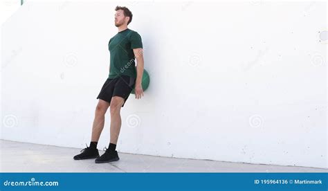 Strength Training Man Doing Squats Using Medicine Ball Rolling On Wall