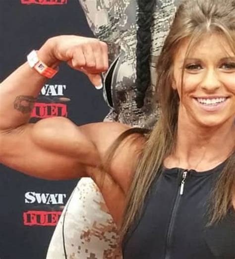 a woman posing for the camera with her arm up and showing off her ripped muscles