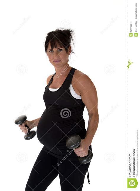 Pregnant Fitness Instructor Lifting Weights Looking At Camera During
