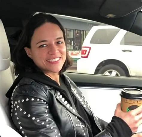 A Woman Sitting In The Back Seat Of A Car Holding A Coffee Cup And Smiling