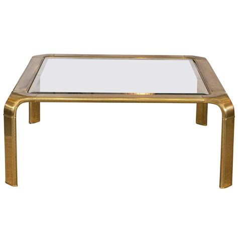 Wear to glass from use. Sensuous 1970's Brass Coffee Table by Mastercraft at 1stdibs