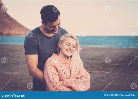 beautiful caucasian couple in love hugging and enjoy the beach and the ocean in vacation leisure
